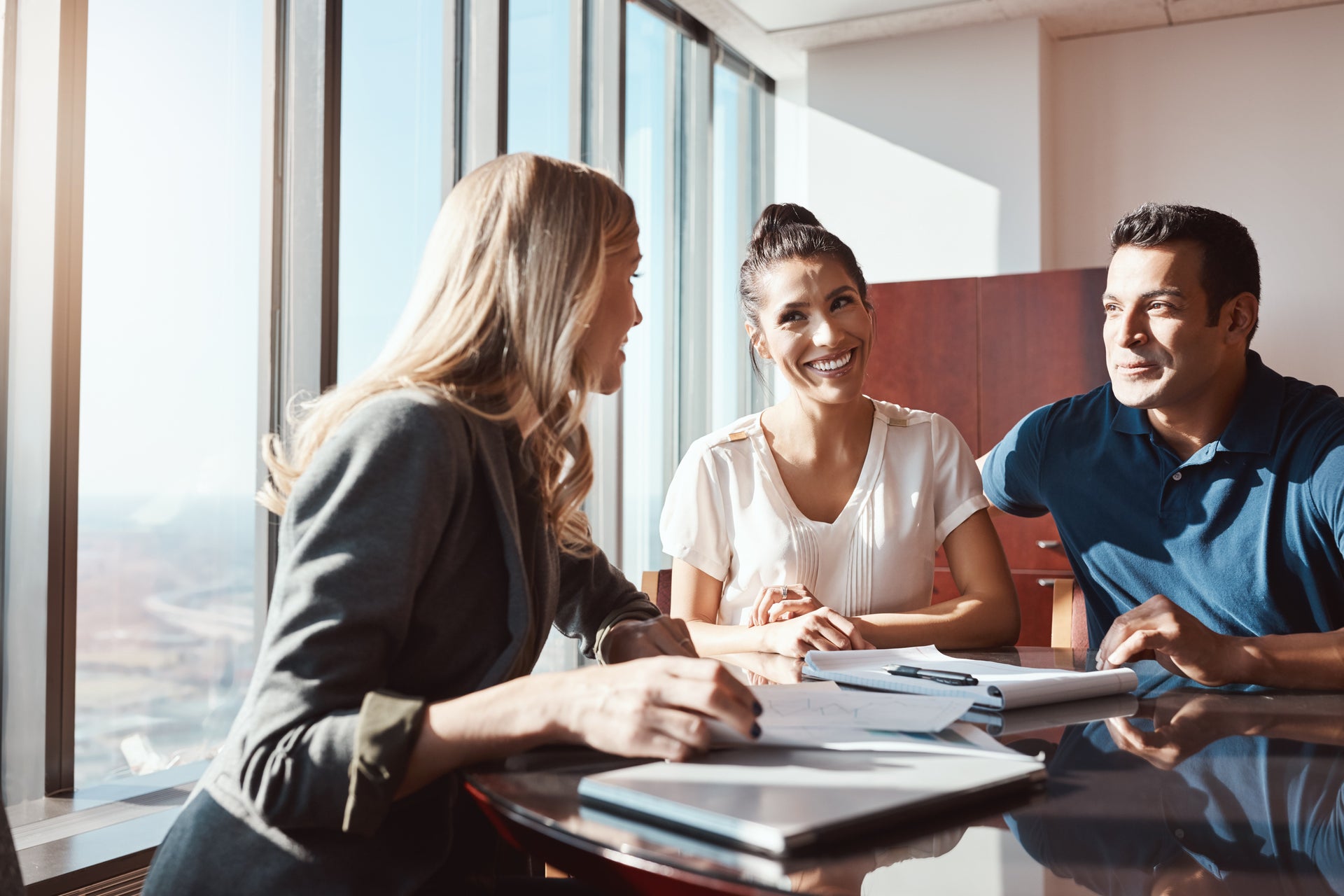 Asesor inmobiliario explicando proceso de compraventa a una pareja